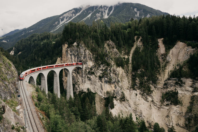 Red train going through the landwasser viadukt in switzerland