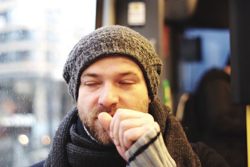 Close-up of young man coughing in bus