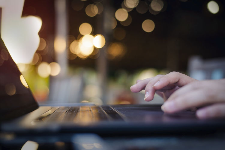 Cropped hands of person using laptop