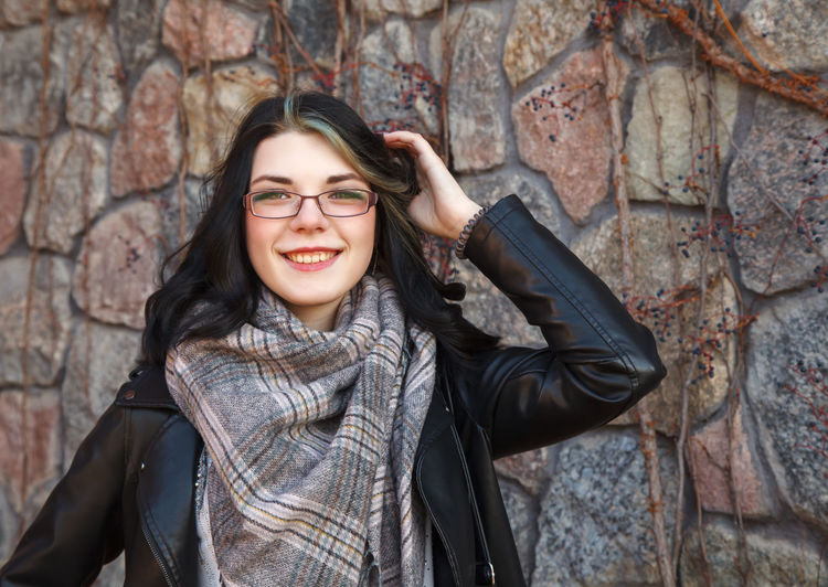 Portrait of young woman standing against rock