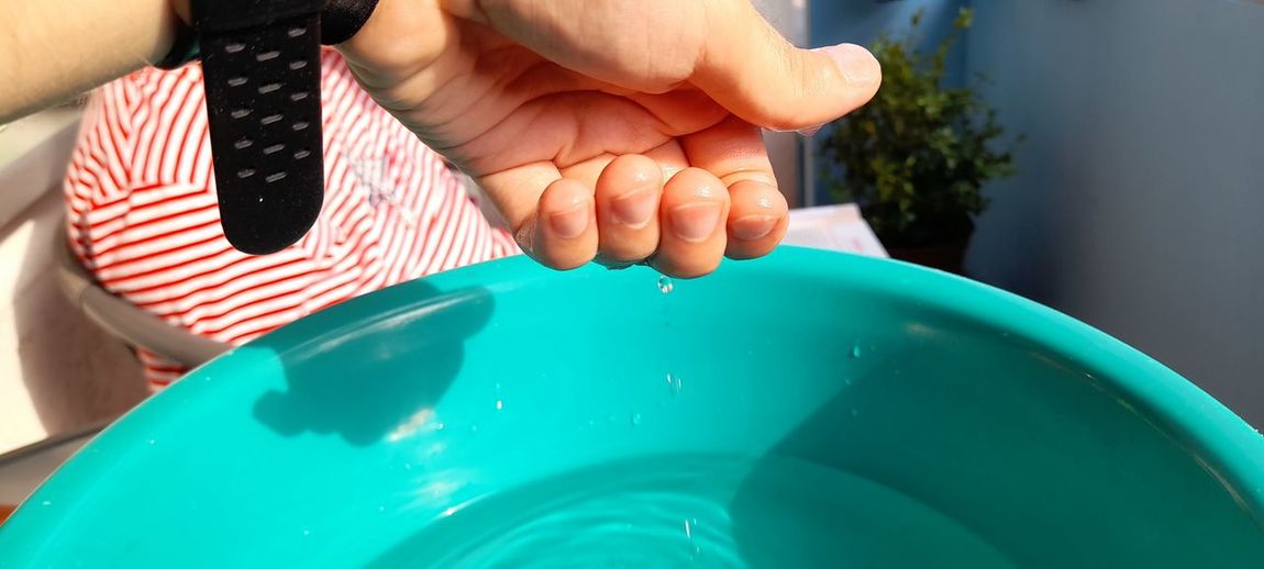 Close-up of water falling from hand in bucket