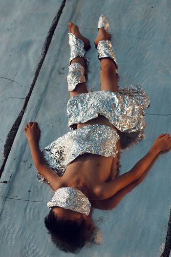 High angle view of naked boy covered with aluminum foils on field