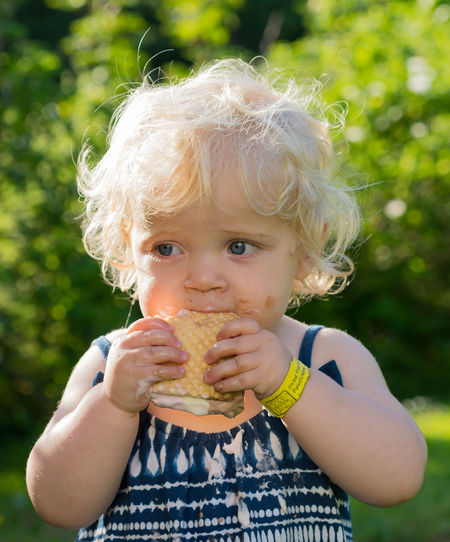 Cute baby girl looking away while eating ice cream
