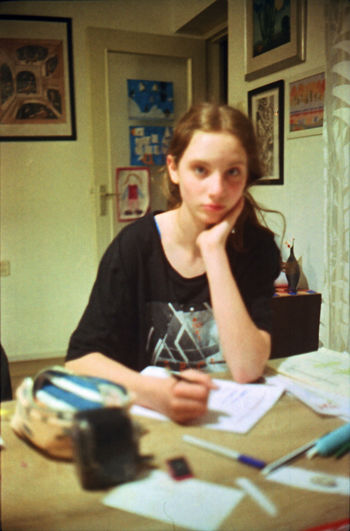 Portrait of teenage girl sitting on table at home