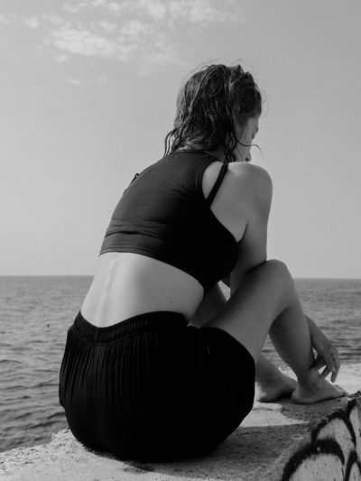 Rear view of woman sitting on beach