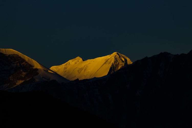Scenic view of snowcapped mountains against clear sky at night