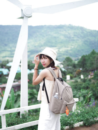 Young woman wearing hat standing against landscape