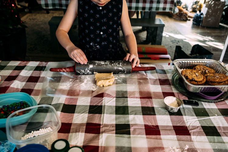 Young girl rolling out cookie dough on dining room table