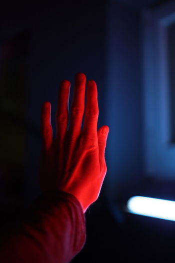 Close-up cropped hand with red light falling on it at home