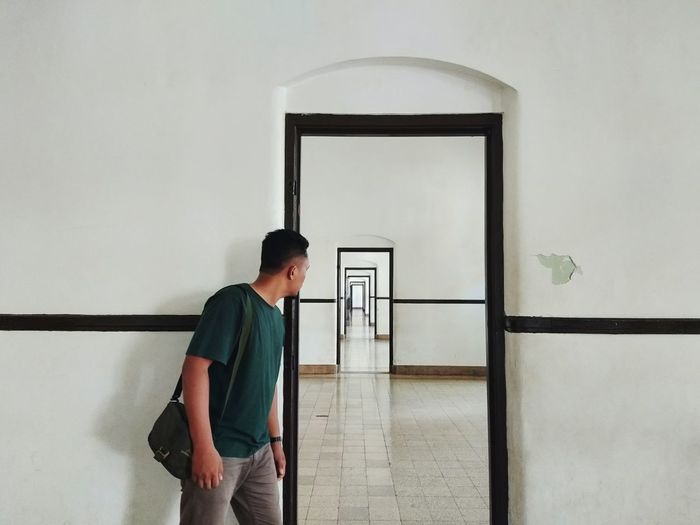 Young man looking at corridor through door