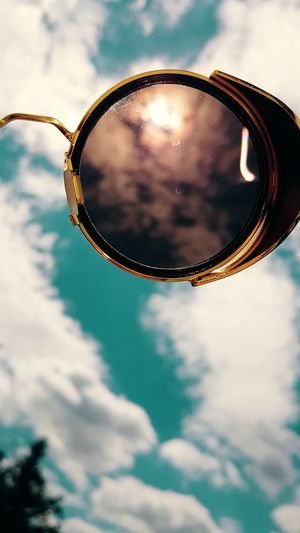 Low angle view of cloudy sky seen through vintage sunglasses