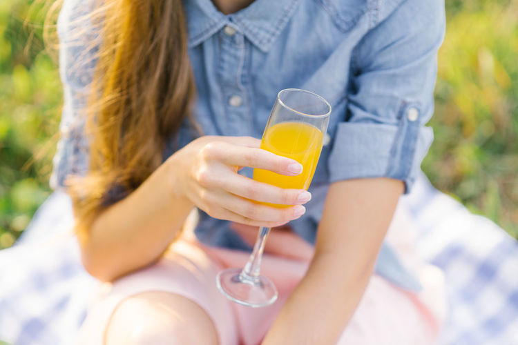 Glass of orange juice in the hand of a young woman person