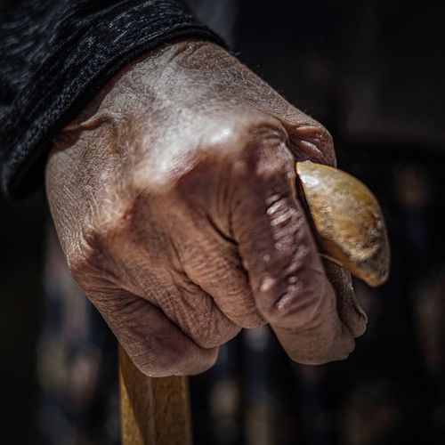 Cropped hand of man holding walking cane