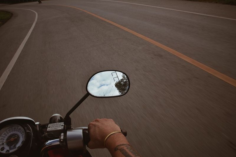 Cropped hand riding motorcycle on road