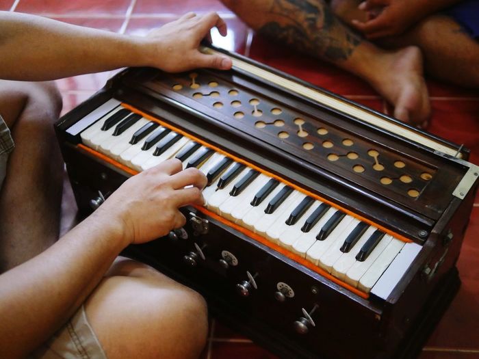 Midsection of man playing harmonium on tiled floor