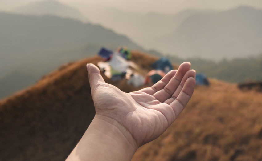 Close-up of hand against mountain