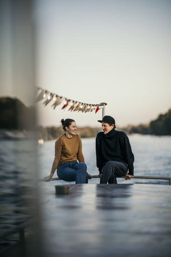 Man with woman sitting on railing of boat at dusk