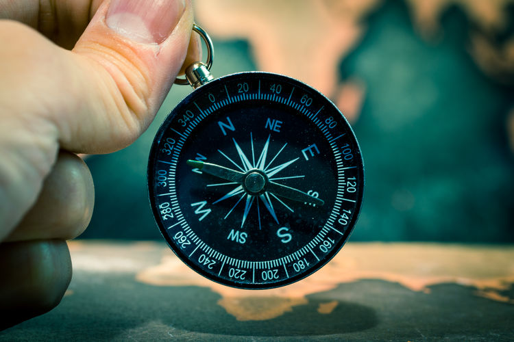 Cropped hand holding compass against world map