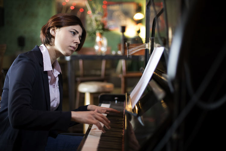 Side view of woman playing piano