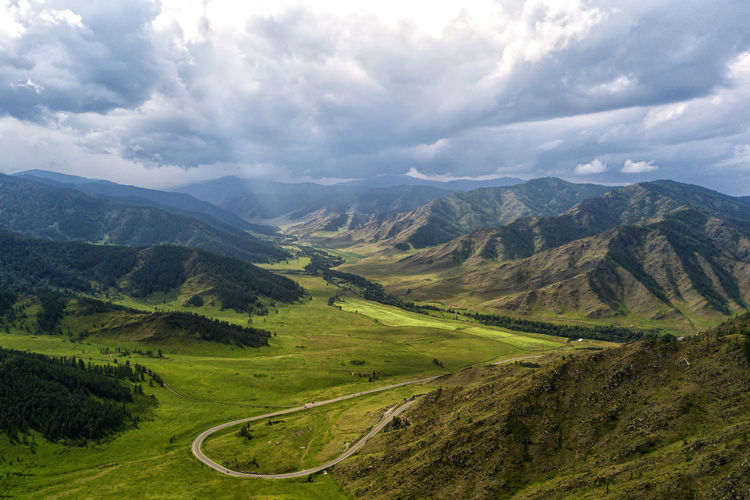 Highway through the mountains, high mountains and a green forest on a warm summer day on each side. 