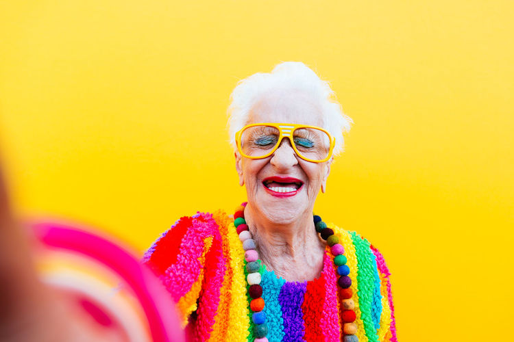 Smiling woman wearing colorful clothing against yellow background