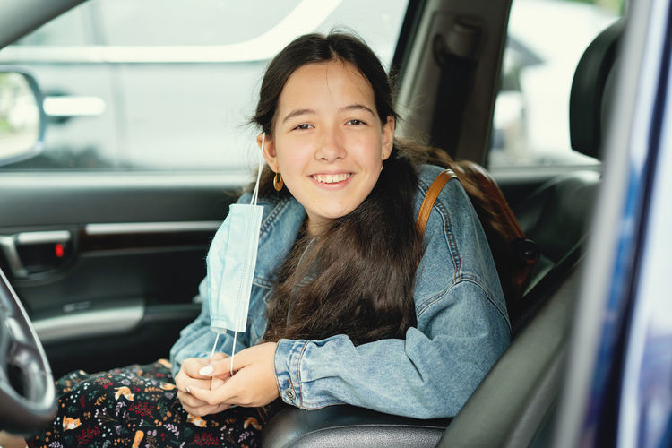 Portrait of smiling woman sitting in car with protective face mask