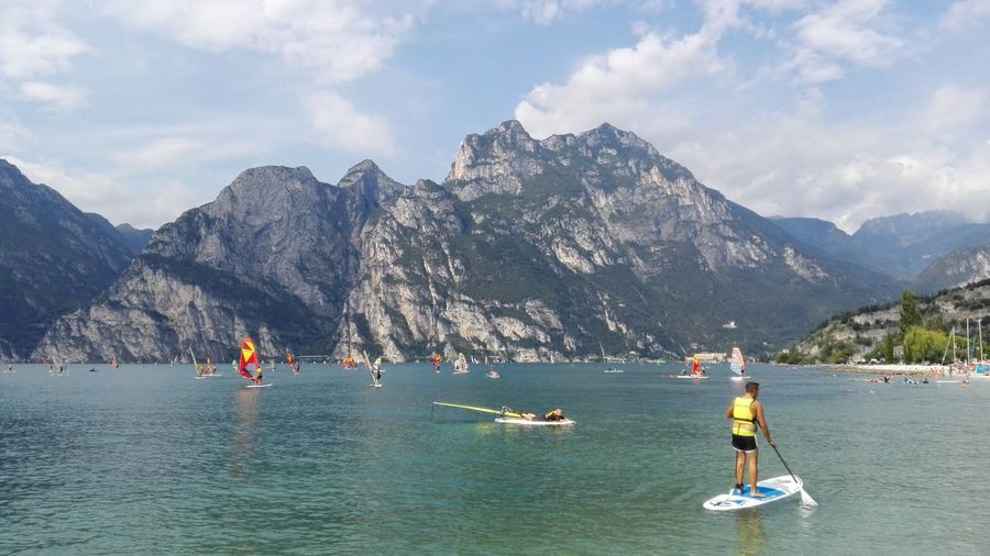 Man paddle boarding in sea against mountains