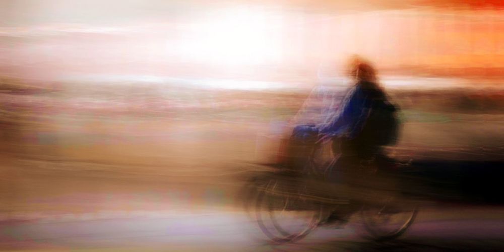 Blurred motion of man riding bicycle on road in city