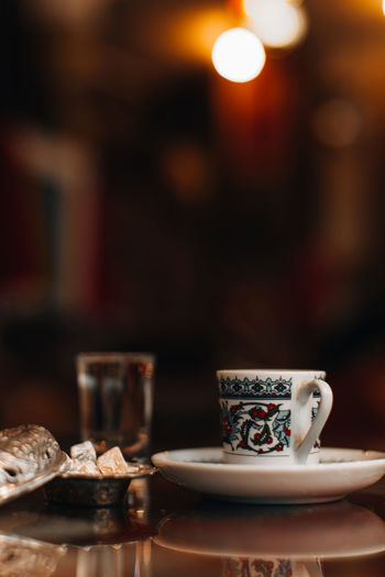 A cup of traditional black strong turkish coffee, sweets delight and a small glass of water.