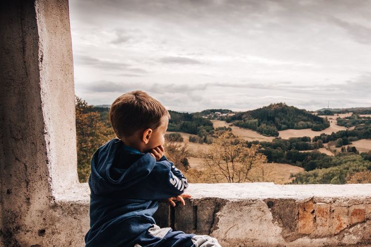 Side view of boy looking at landscape against sky