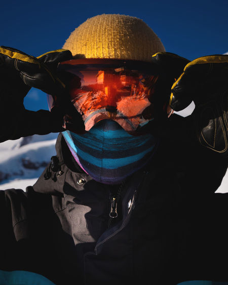 Close-up of men's ski goggles with reflection of snowy mountains. man against the blue sky. winter