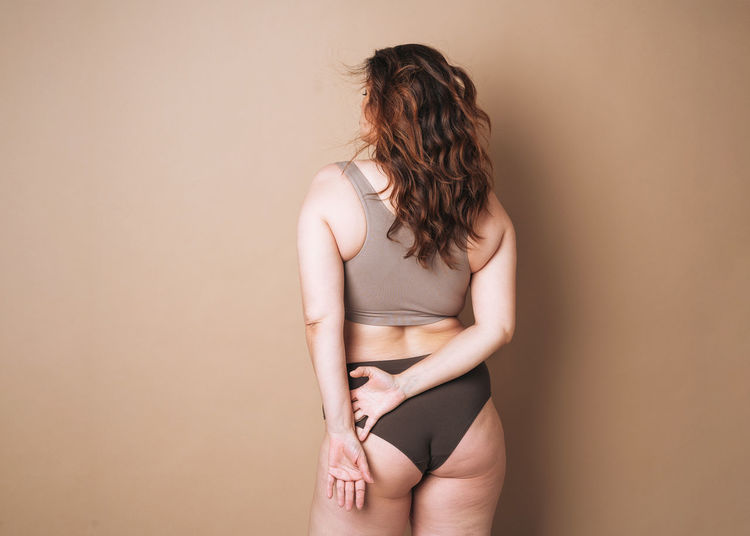 Midsection of young woman standing against wall