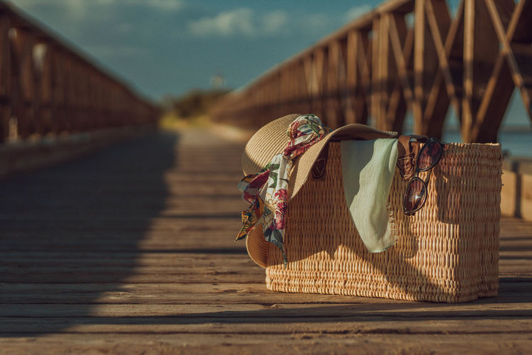 Close-up of stray bag and hat on wooden bridge