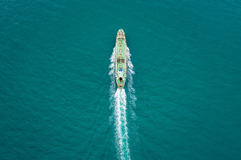 Aerial top view green oil ship tanker full speed with beautiful wave and splash water in line 