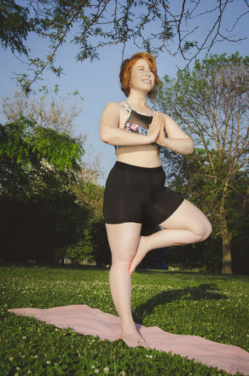 Low angle view of woman practicing tree pose yoga at park
