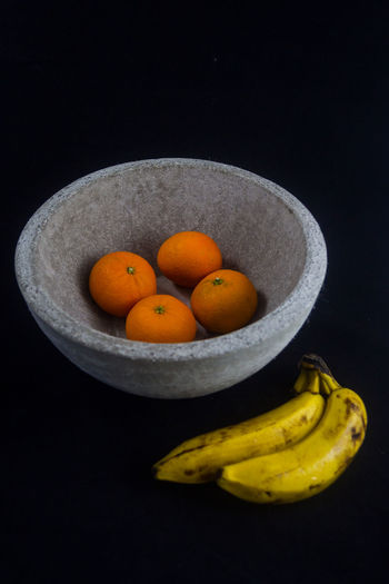 Close-up of fruits in plate against black background