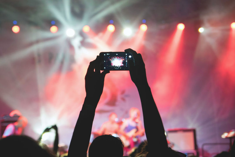 Silhouette hands photographing music concert with smart phone