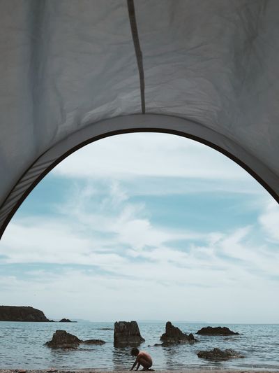 Girl on beach seen through tent against sky