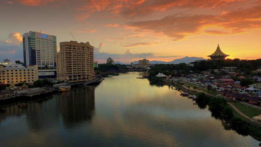 River amidst city against sky during sunset