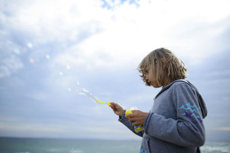 Low angle view of girl playing with bubbles at huntington beach