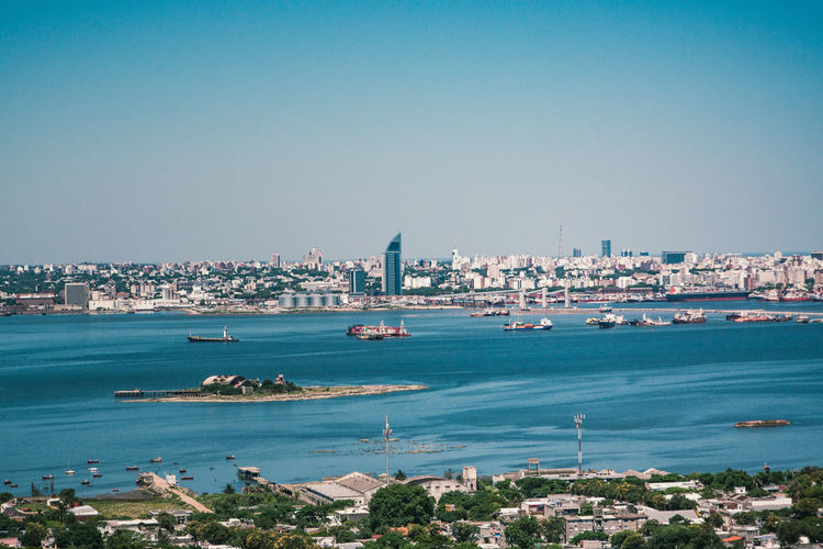 View of city at waterfront against blue sky