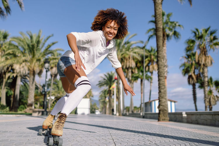 Full length of young woman roller skating on street in city during sunny days