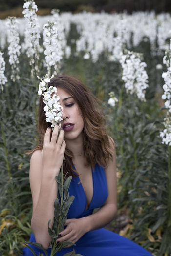 Beautiful young woman with flower petals on plants