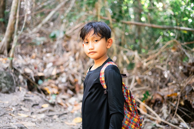 Portrait of boy standing on land in forest