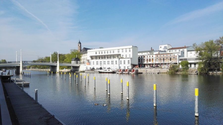 Sailboats in river by buildings against sky