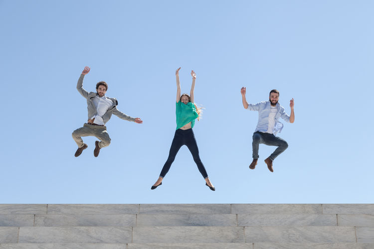 Group of people jumping against clear sky