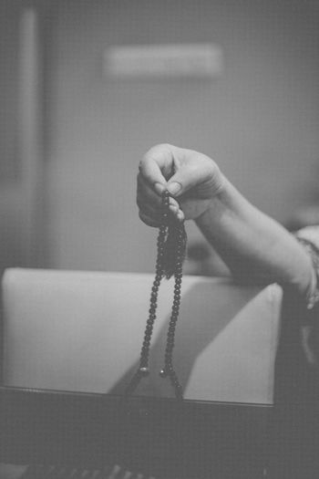 Cropped hand holding prayer beads seen through glass