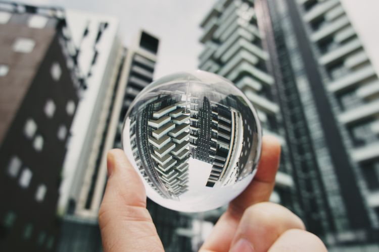 Close-up of person holding crystal ball against buildings 