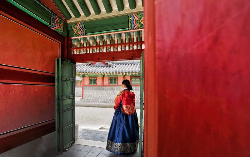 Rear view of woman standing in traditional clothing at doorway