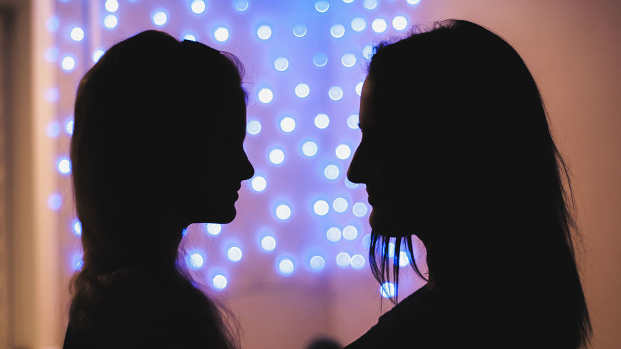 Silhouette lesbian couple against illuminated background